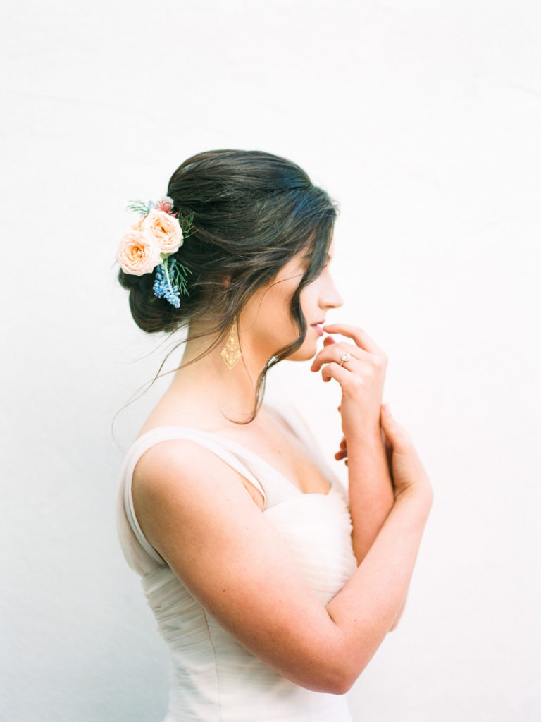 woman in profile wore flowers in her hair with fingertips lightly touching her lips